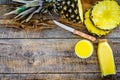Preparing pineapple juice. Bottle with beverage near fruit slices and knife on wooden background top view copyspace Royalty Free Stock Photo
