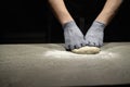 Preparing pizza dough.Male baker's hands in rubber gloves knead dough for Italian pizza on the work table. Baking process