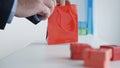 Preparing a Present for a Birthday in a Gift Shop, Putting Small Present Boxes in a Colored Paper Bag Royalty Free Stock Photo