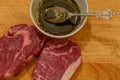 Preparing raw meat for cooking. Two slices of raw meat along white bowl with sauce over counter table. . Royalty Free Stock Photo