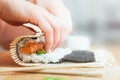 Preparing, rolling sushi. Salmon, avocado, rice and chopsticks on wooden table. Royalty Free Stock Photo