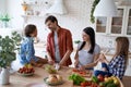 Preparing a salad. Lovely family of four cooking together in the modern kitchen at home Royalty Free Stock Photo