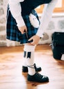 Preparing for a Scottish wedding. Man in high socks, sporran and shoes with long laces attaches a small sword to the