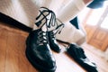 Preparing for a Scottish wedding. Man in a kilt, high socks and shoes laced with long laces. Nearby a pair of black
