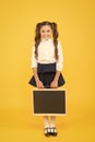 Preparing small child for school. Small girl holding black-board on yellow background. Small kid with empty chalkboard