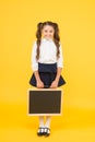 Preparing small child for school. Small girl holding black-board on yellow background. Small kid with empty chalkboard