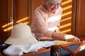 Preparing suitcase for summer vacation trip. Elderly woman checking accessories and stuff in luggage on the bed at home before Royalty Free Stock Photo