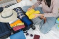 Preparing suitcase for summer vacation trip. woman checking accessories and stuff in luggage on the bed at home before Royalty Free Stock Photo