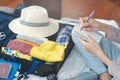 Preparing suitcase for summer vacation trip. Young woman checking accessories and stuff in luggage on the bed at home. Royalty Free Stock Photo