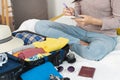Preparing suitcase for summer vacation trip. Young woman checking accessories and stuff in luggage on the bed at home. Royalty Free Stock Photo