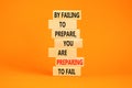 Preparing symbol. Concept words By failing to prepare you are preparing to fail on wooden blocks on a beautiful orange table