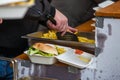 Preparing take away meal portion with freshly cooked burger and french fries on outdoors kitchen at street music festival