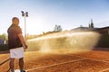 Preparing a tennis court for the match. A man is watering a field with a hose