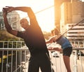 Preparing their muscles for action. two sporty young people warming up before a run. Royalty Free Stock Photo