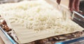 Preparing traditional italian lasagna adding cheese Royalty Free Stock Photo