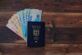 Stack of Israeli money bills in the amount of 200 shekels and an Israeli passport on a wooden table Royalty Free Stock Photo