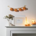 Preparing your home for Halloween. A garland of pumpkins on the wall above fake dresser panel. Frame with the inscription, orange