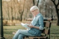 Prepossessing elderly madam in glasses reading intently a book