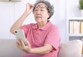 Presbyopia, senior asian woman holding eyeglasses having problem with vision problem trying to read text on mobile phone