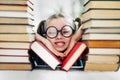 Preschool age girl with dimples in big funny glasses among a pile of books Royalty Free Stock Photo