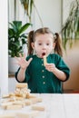 Preschool age girl expressive reaction on unexpected falling of wooden block tower. She is looking on last wooden block