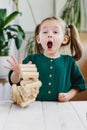 Preschool age girl expressive reaction on unexpected falling of wooden block tower