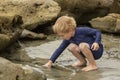 Preschool aged boy in a blue swimming suit playing in tidepools at the beach Royalty Free Stock Photo