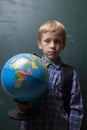 preschool boy holds globe on blackboard background Royalty Free Stock Photo