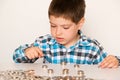 A preschool boy in a plaid shirt counts coins, builds towers. Financial literacy for children.