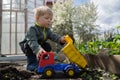 Preschool boy playing with a toy truck between the beds in the garden. Royalty Free Stock Photo