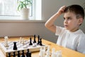 A preschool boy ponders his move in a chess game. Board game Royalty Free Stock Photo