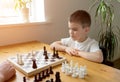 A preschool boy ponders his move in a chess game. Board game. Royalty Free Stock Photo