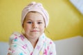 Preschool child after bath. Cute little girl with wet curly hair wearing a bathrobe and head towel sitting on bed Royalty Free Stock Photo