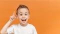 Preschool child boy have great idea. Finger pointing up a great idea isolated on orange background. Close-up portrait of Royalty Free Stock Photo
