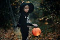 Preschool child with halloween costume and jack` o` lantern in a forest, scary skelleton