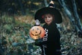 Preschool child with halloween costume and jack' o' lantern in a forest, scary skelleton