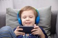 Preschool child listens to music on a smartphone while lying at home on the bed, boy plays on the phone Royalty Free Stock Photo
