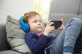 Preschool child listens to music on a smartphone while lying at home on the bed, boy plays on the phone Royalty Free Stock Photo