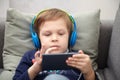 Preschool child listens to music on a smartphone while lying at home on the bed, boy plays on the phone Royalty Free Stock Photo