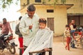 Preschool child with unhappy face doing new hairstyle by village barber