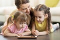 Children and their mom lying on floor in living room with tablet pc