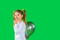 Preschool girl hides a ultimate grey color balloon showing quietly tsss to the camera. Green background and side space Royalty Free Stock Photo