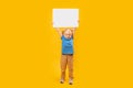 Preschool girl holds white board above her head. Child with white paper Place for your text. Copy space, mockup Royalty Free Stock Photo