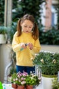 Preschool girl pruning balcony flowers with pruning shears Royalty Free Stock Photo