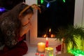 a preschool girl sits on the window at Christmas and make a wish. candles are nearby Royalty Free Stock Photo