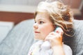 Preschool girl takes temperature and feeling sick. Happy toddler child measuring with infrared in ear thermometer at Royalty Free Stock Photo