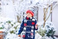 Funny little kid boy in colorful clothes playing outdoors during strong snowfall Royalty Free Stock Photo