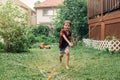 Preschool kid boy splashing with gardening hose on backyard at summer day. Child playing with water outside at a home yard. Candid Royalty Free Stock Photo