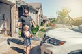 Preschool little Caucasian girl washing car on driveway in front house on sunny summer day Royalty Free Stock Photo