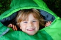 Preschool little girl in sleeping bag camping. Outdoors activity with children in summer. Fun and adventure camp, family
